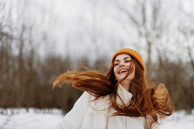 Cheerful woman wearing knit hat enjoying in snow