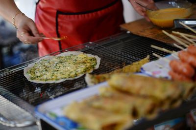 Close-up of person preparing food on barbecue grill