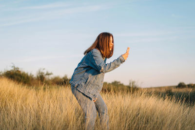 Side view of woman standing on field against sky