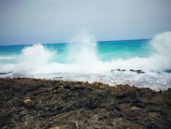 Waves splashing on shore against sky