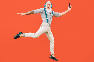 Low angle view of woman jumping against red background