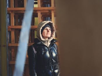 Portrait of young woman standing against building in winter