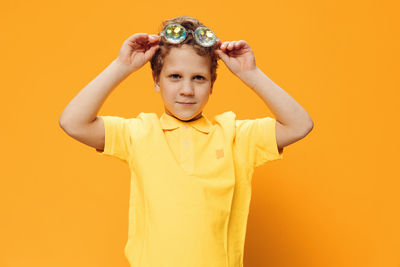 Portrait of woman holding hat against yellow background