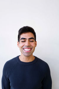 Portrait of young man standing against white background