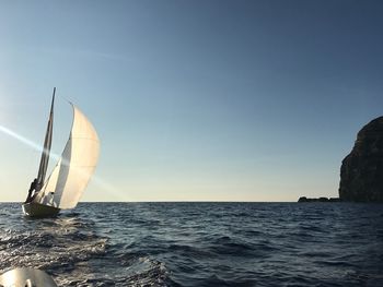 Sailboat sailing in sea against clear sky