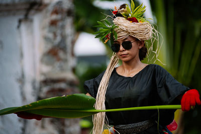 Young woman wearing sunglasses holding plant