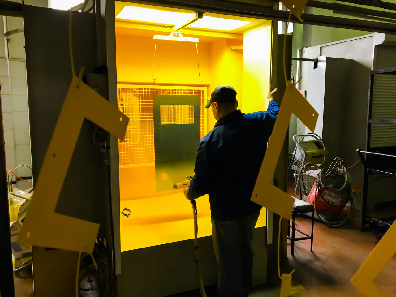 REAR VIEW OF MAN WORKING AT ILLUMINATED UNDERGROUND