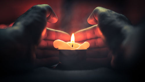 Close-up of hand holding lit candle