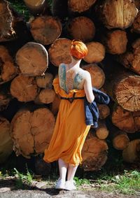 Full length of woman standing by logs