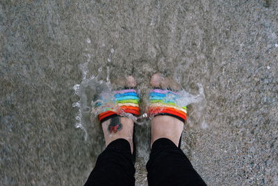 Low section of person standing on multi colored water