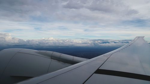 Cropped image of airplane against cloudy sky