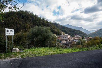 Road by trees and mountains against sky