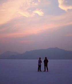 Rear view of people on mountain against sky during sunset