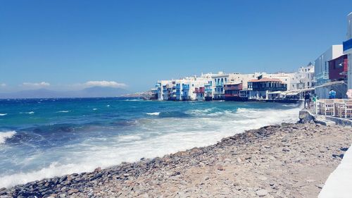 Scenic view of sea and buildings against blue sky