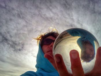 Low angle view of mid adult woman holding crystal ball with reflection