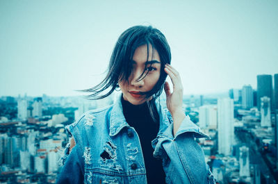 Young woman wearing sunglasses standing against clear sky