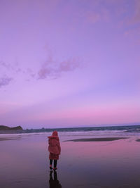 Rear view of woman standing on beach during sunset