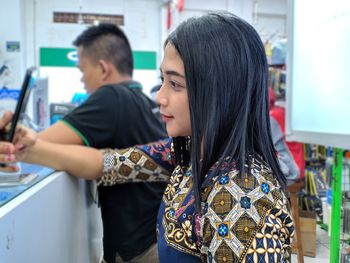 Side view of young woman doing selfie at store