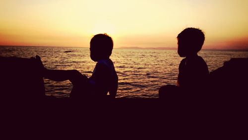 Silhouette of people on beach at sunset