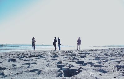 Rear view of people on beach against clear sky