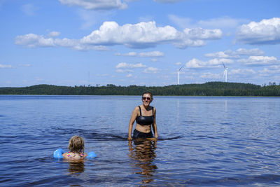Portrait of woman and daughter in lake against sky