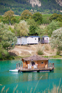 Boats in river by buildings against trees