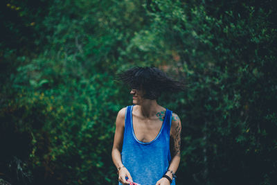 Young woman standing against trees in forest