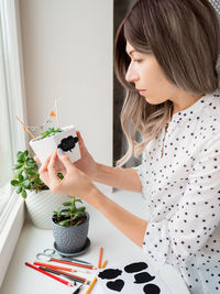 Smiling woman shows handmade decorations for halloween. diy flags and boo sticker on flowerpot