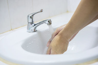 Young woman washing hands with soap over sink in bathroom, closeup