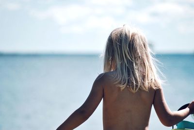 Rear view of woman at beach against sky