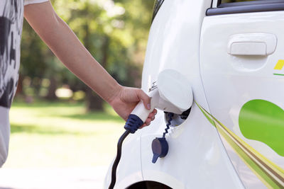 Midsection of man charging electric car