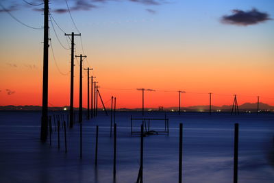 Silhouette of poles against sky during sunset