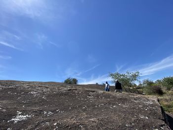 Rear view of people on mountain against blue sky