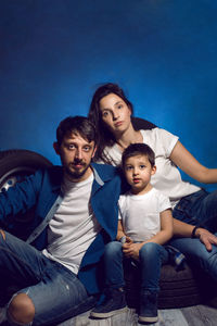 Family of three on a blue background with wheels in the studio