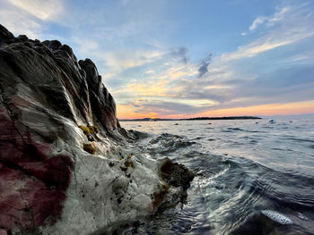 Rock formation on beach against sky during sunset