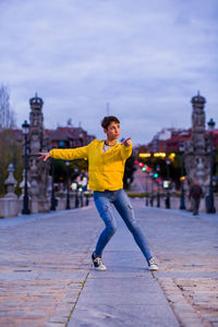 Full length portrait of smiling man in city against sky