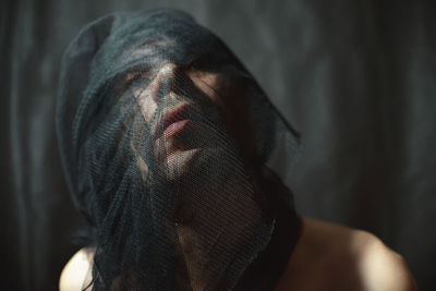 Close-up of man wrapping net over face at home