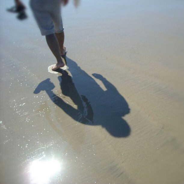 low section, lifestyles, person, leisure activity, men, walking, sunlight, standing, beach, shadow, human foot, unrecognizable person, sport, sand, outdoors, motion