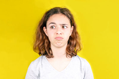 Portrait of teenage girl against yellow background