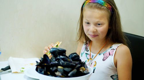 In the restaurant, the kid girl served on the table a large bowl a plate of cooked open blue mussels
