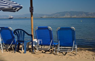 Chairs on beach against blue sky