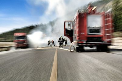 Blurred motion of firefighters spraying water on burning truck