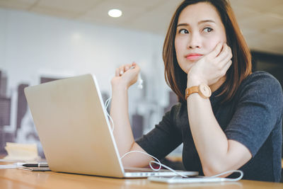 Portrait of young woman using phone while sitting on table