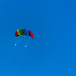 Low angle view of parachute against clear blue sky