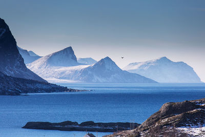 Scenic view of sea and snowcapped mountains against sky