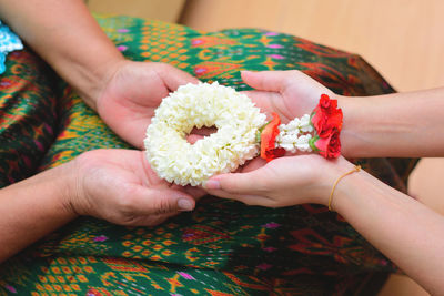 Midsection of woman holding red flower