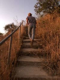 Full length rear view of man walking on footpath