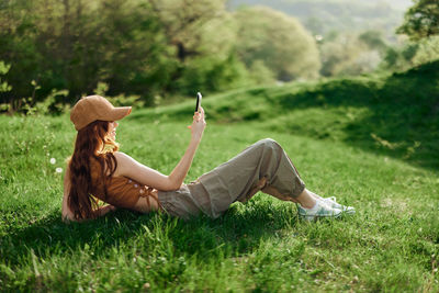 Rear view of woman sitting on grassy field