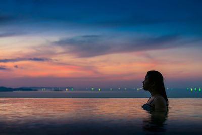 Woman in infinity pool during sunset