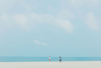 Man with friend photographing at beach against sky